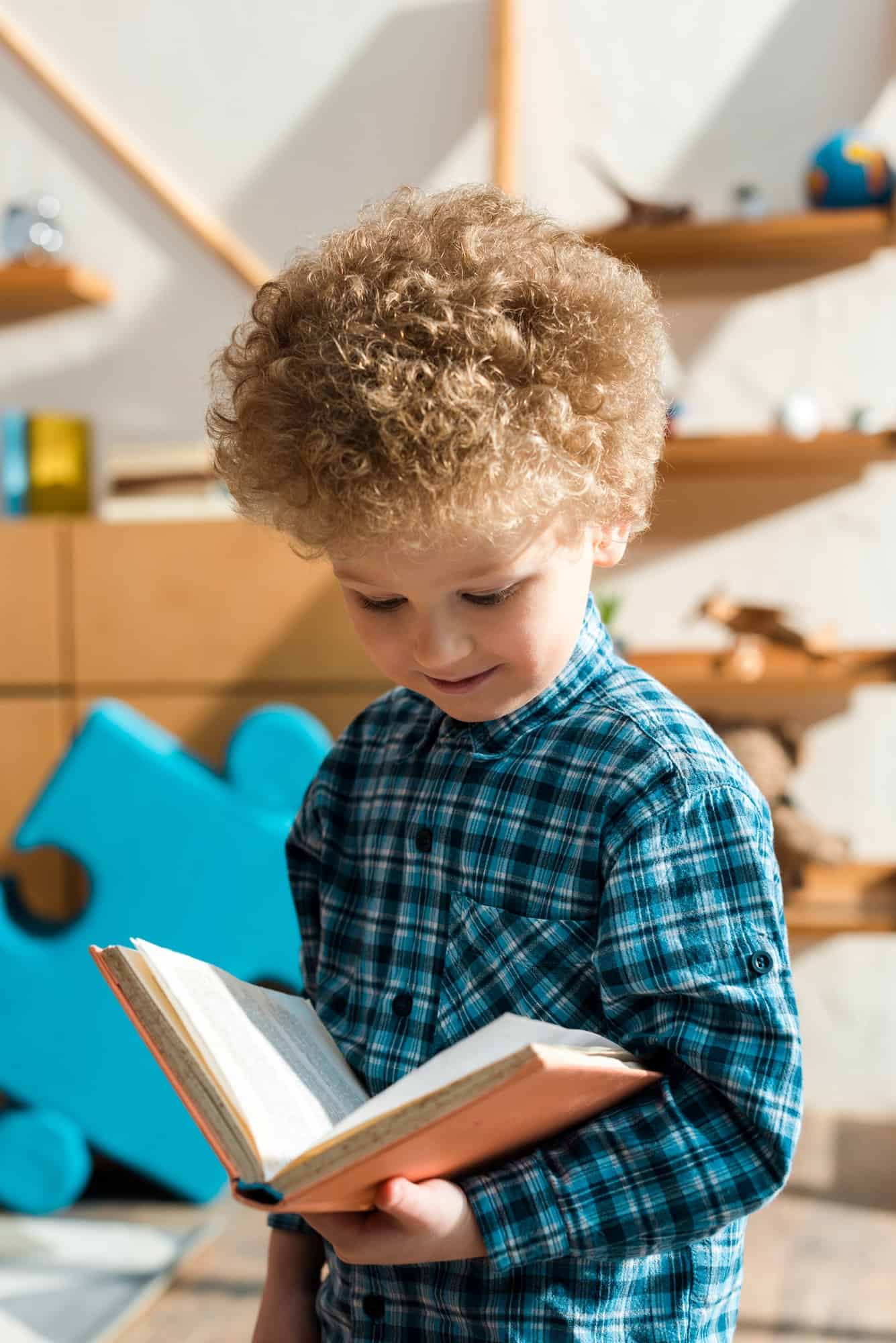 smiling and smart child reading book at home