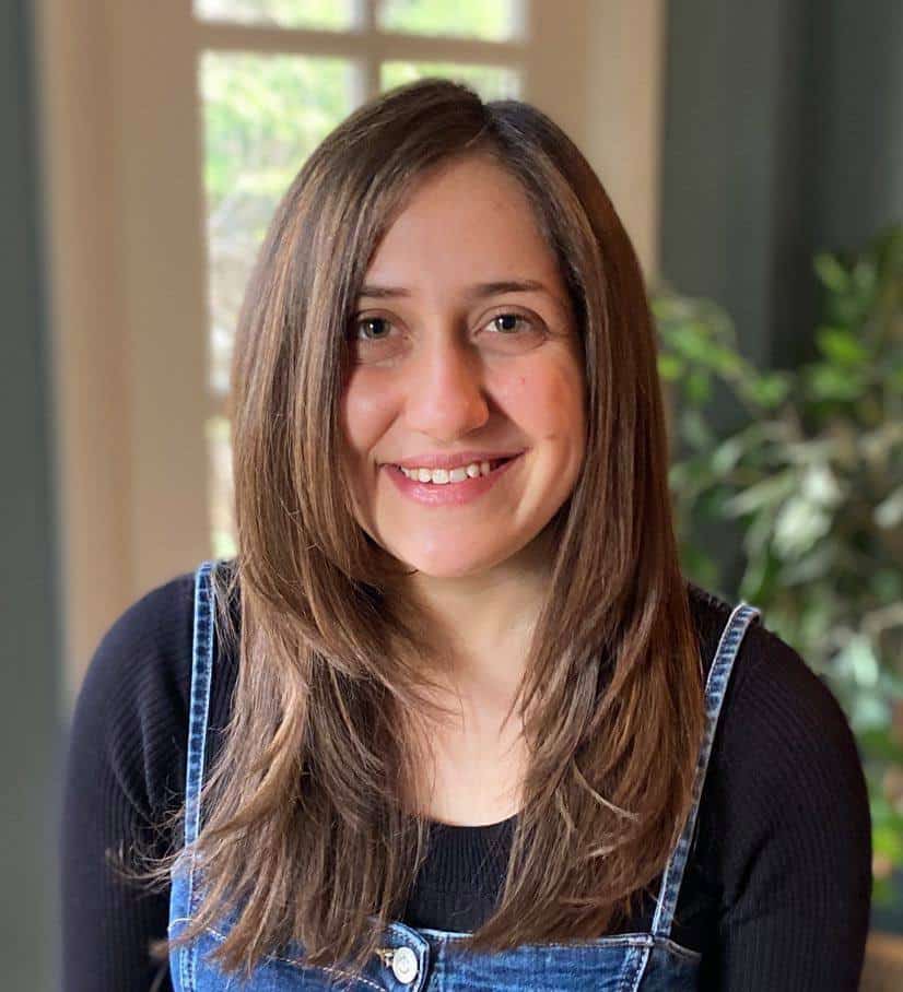 A woman in overalls smiles.